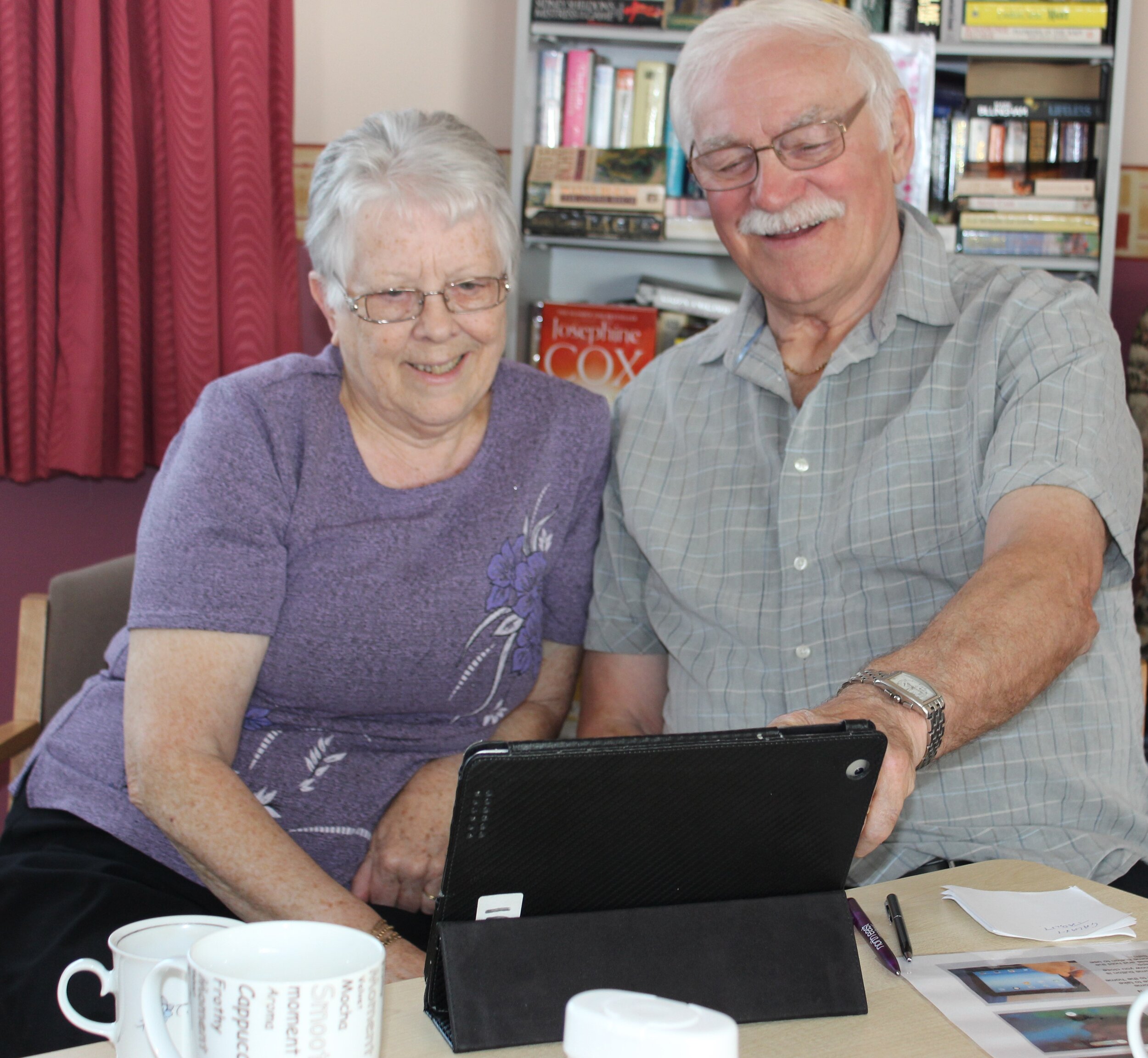 two older people using the ipads to look at photos