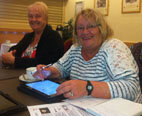 two ladies smiling while using the ipads