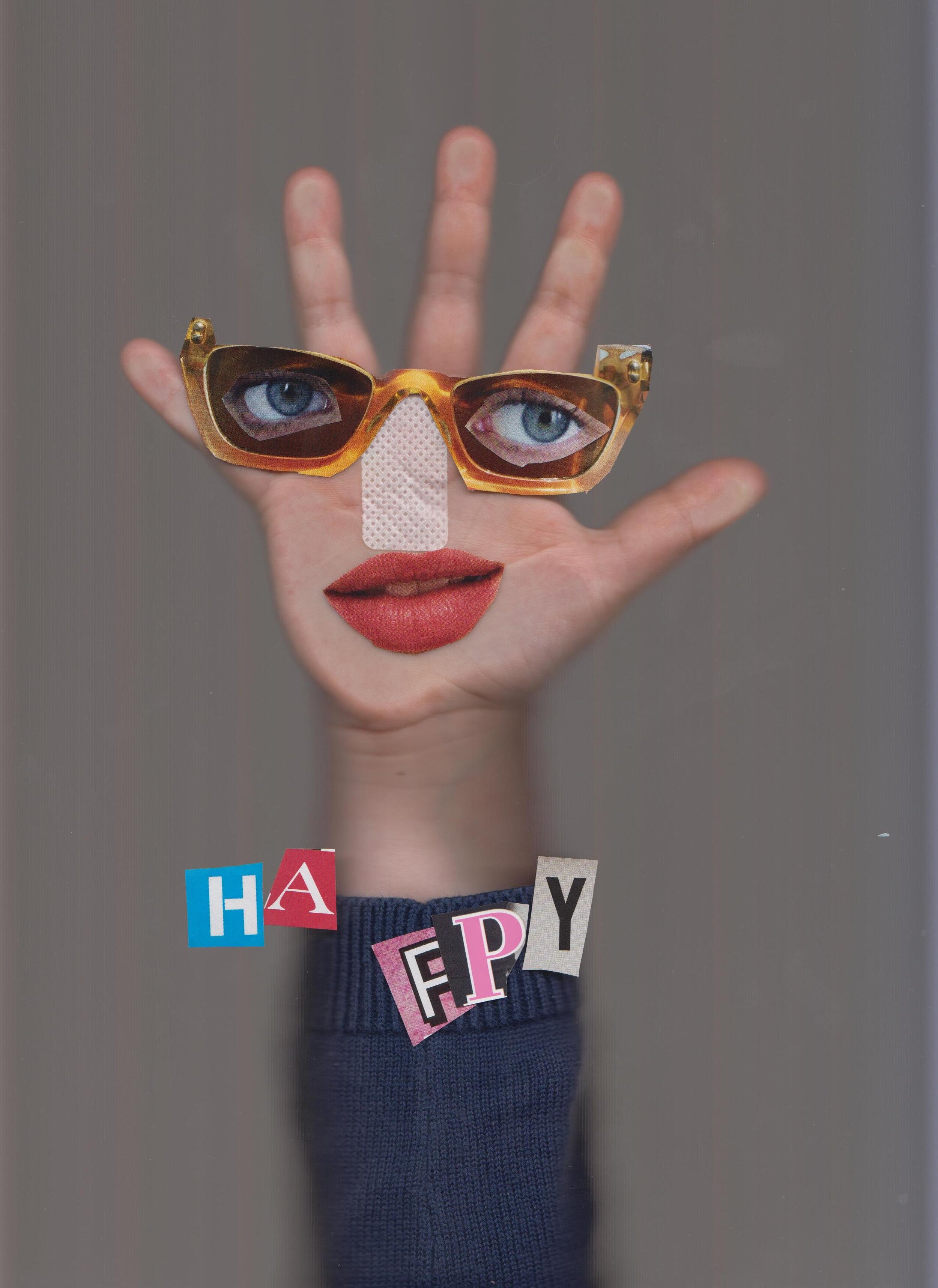 Scan of a hand with maazine cut outs as a face with the word Happy written on it