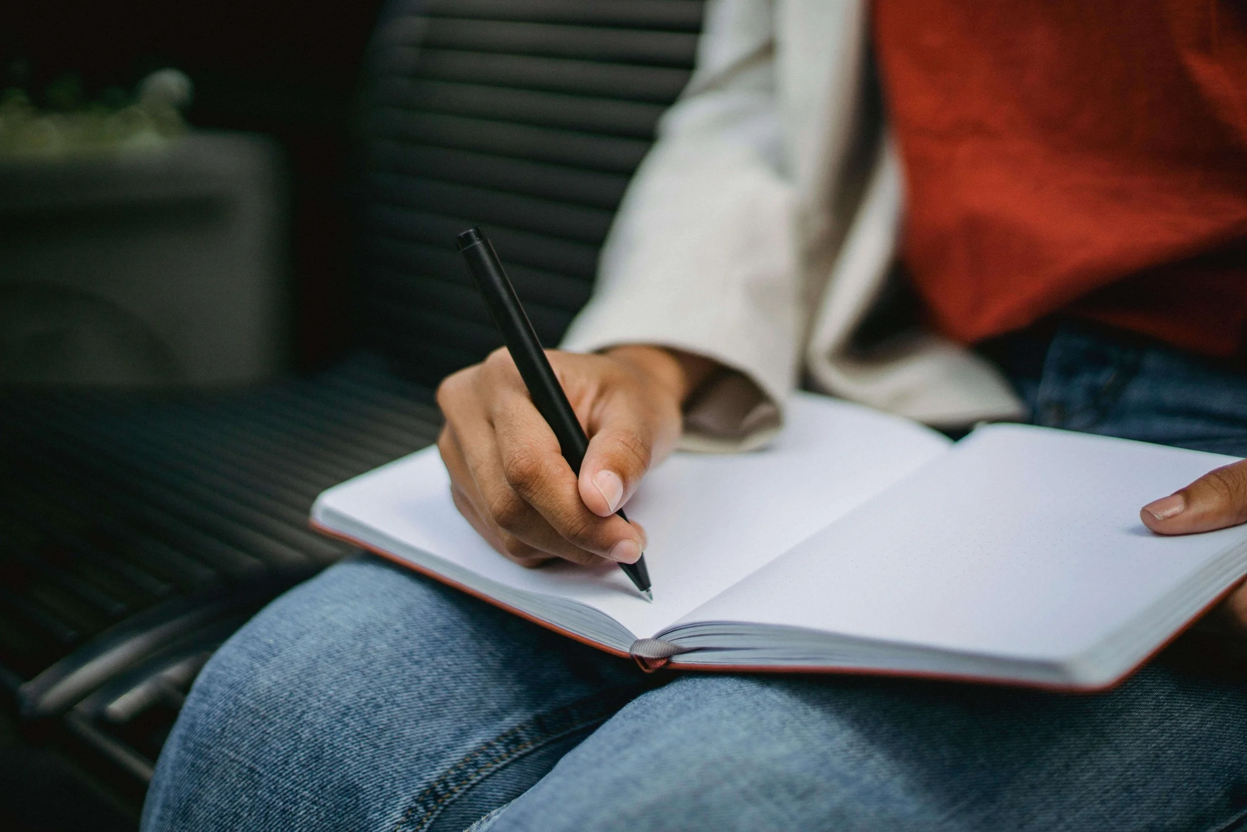 person sitting down and writing in a journal