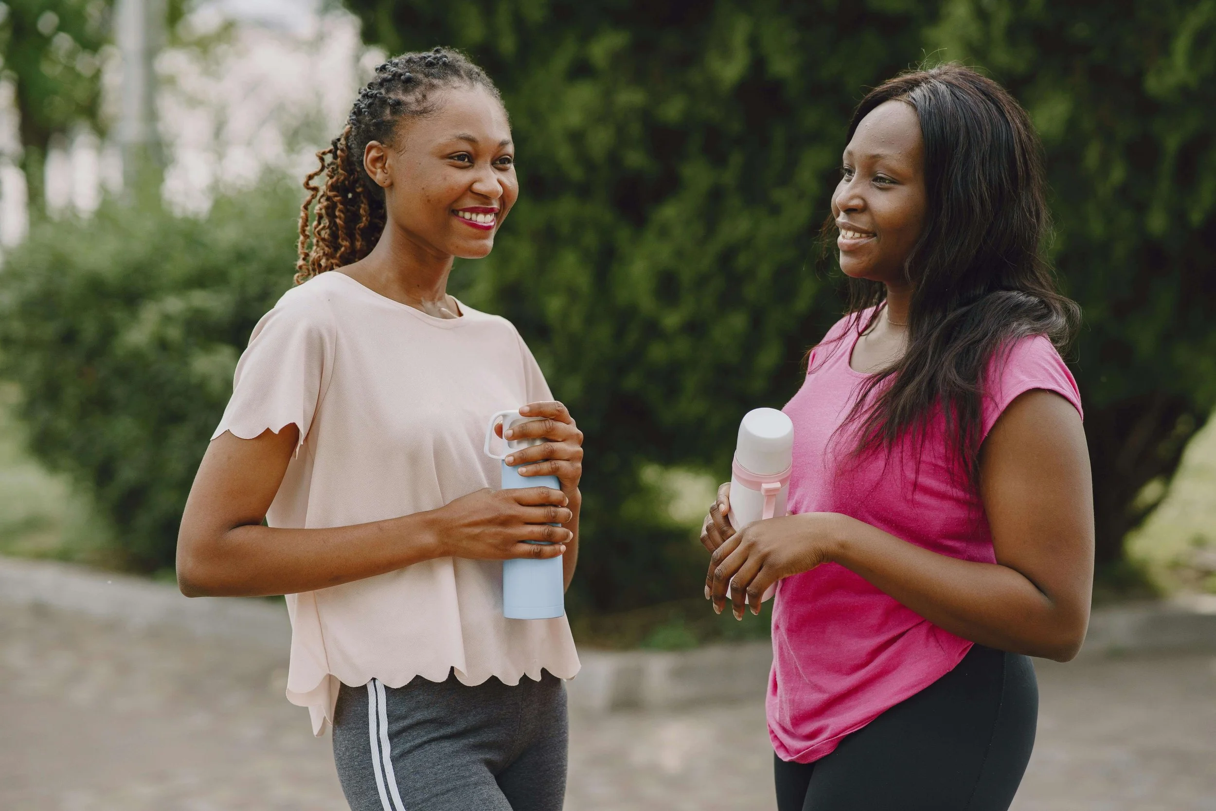 Two women smiling while outside and holding water bottles