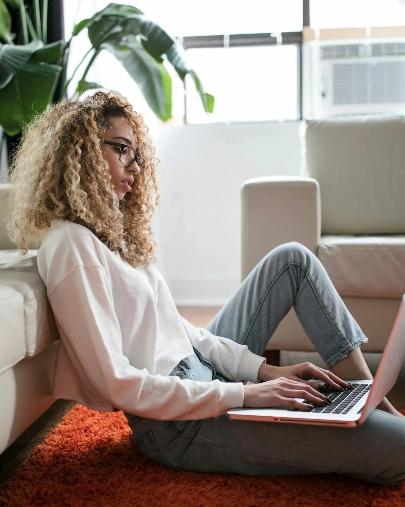 girl sitting in front of a couch using a laptop