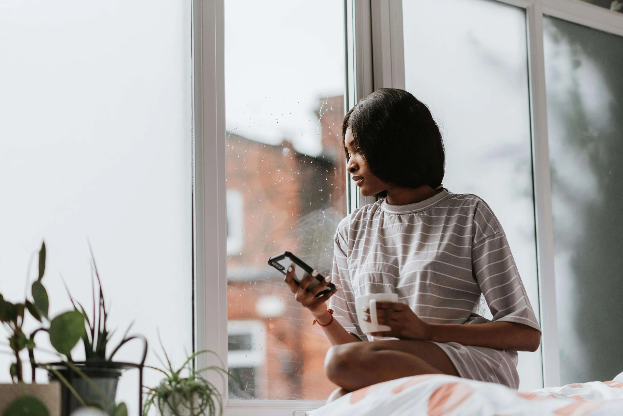Woman holding phone and looking out window