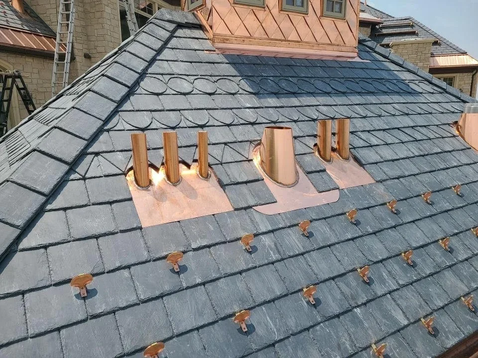 Natural slate roof with copper flashings and roof penetrations.