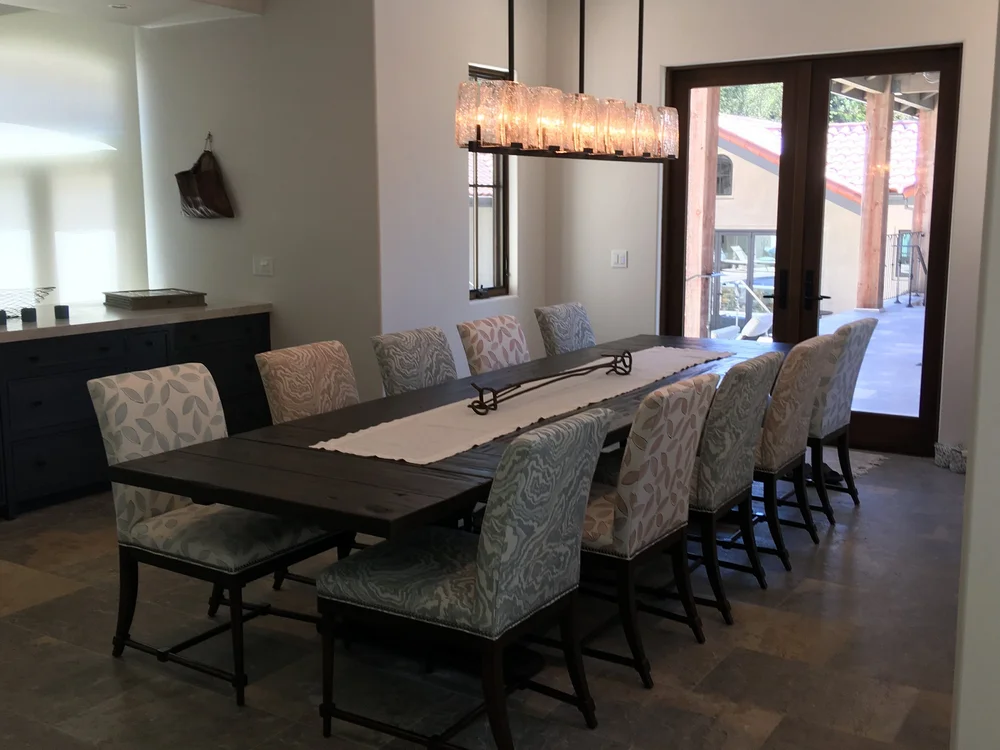  Situated right off the kitchen, the dining room can easily host 10 or more for family gatherings in its custom upholstered chairs and opens to the covered walkway for extended banquette seating outdoors. 