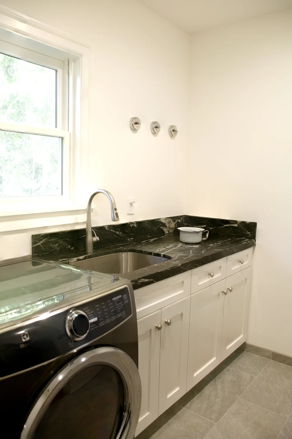  The new laundry room is complete with a sink, a side by side washer and dryer, plenty of storage, and wall mounted stainless steel retractable laundry lines for convenient air drying of clothes. 