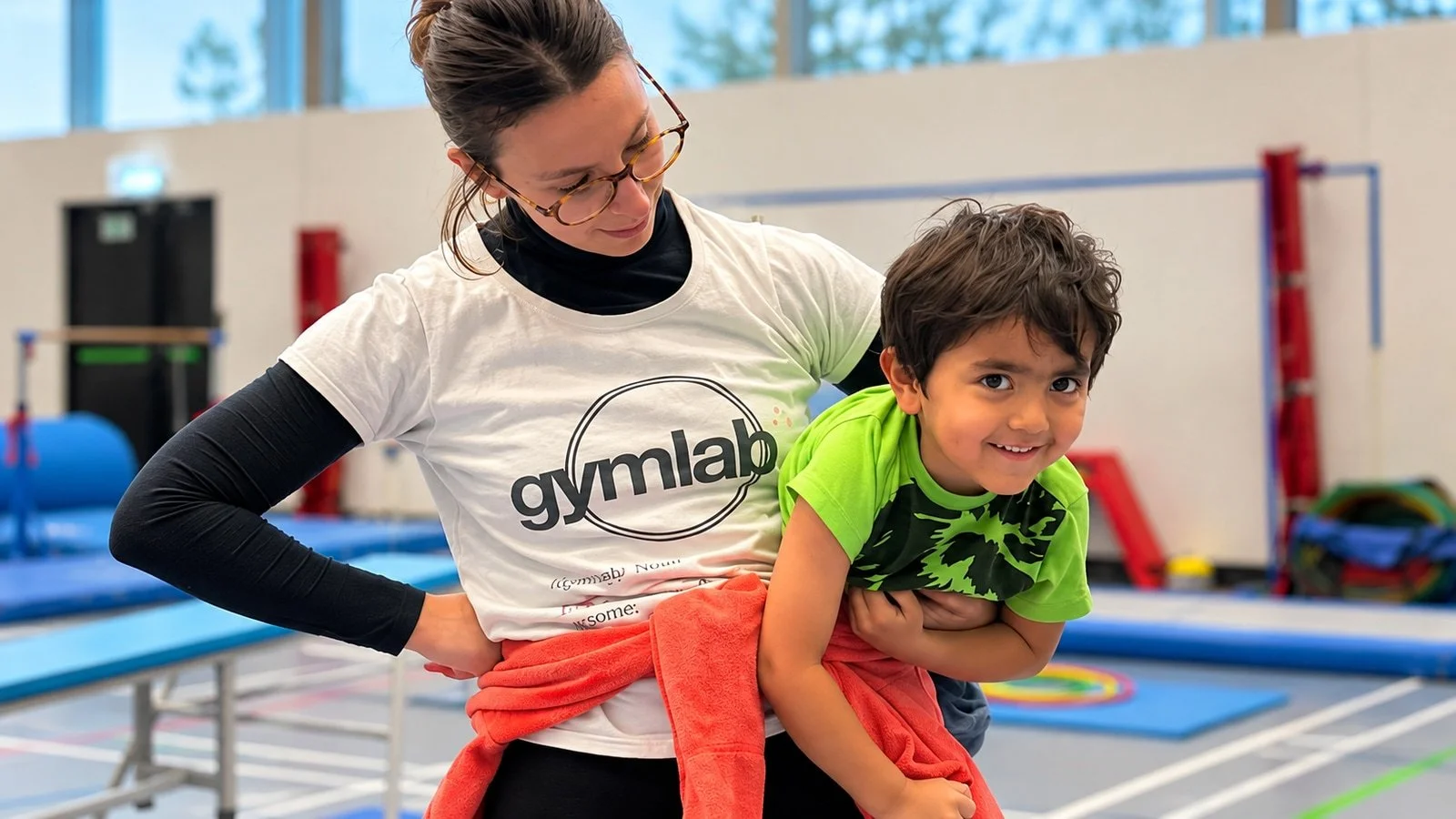 A coach supporting a child during gymnastics; an edited GymLab photograph.