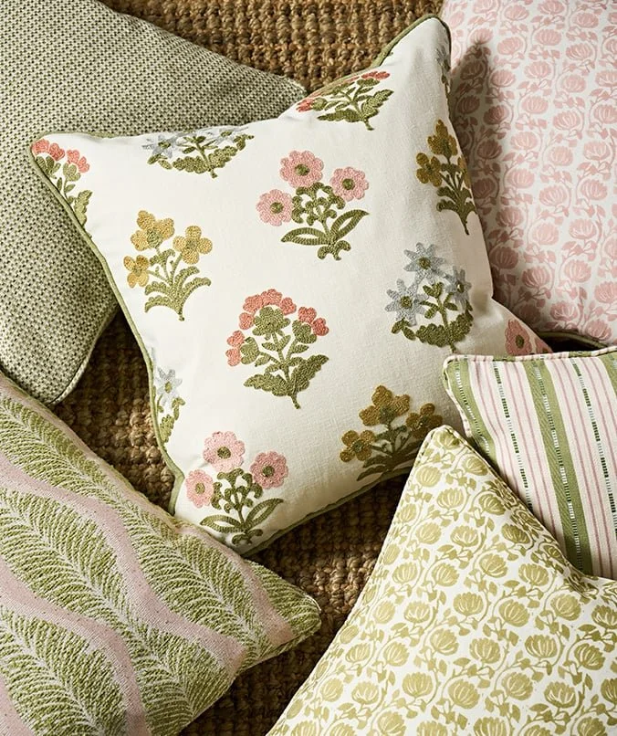 A collection of decorative pillows with floral and leaf patterns on a textured couch.