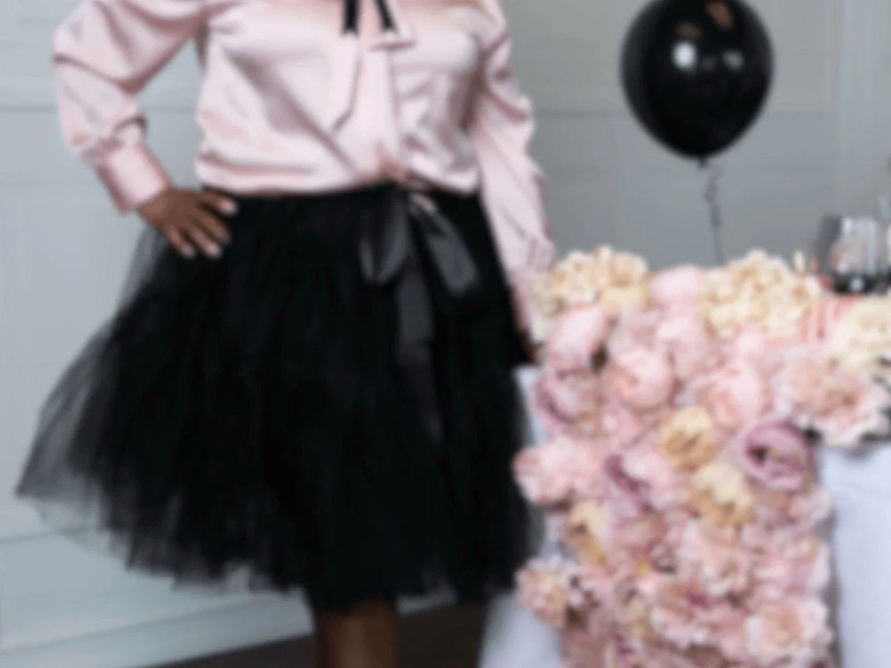 Out-of-focus image of an event designer standing beside a floral installation and styled table
