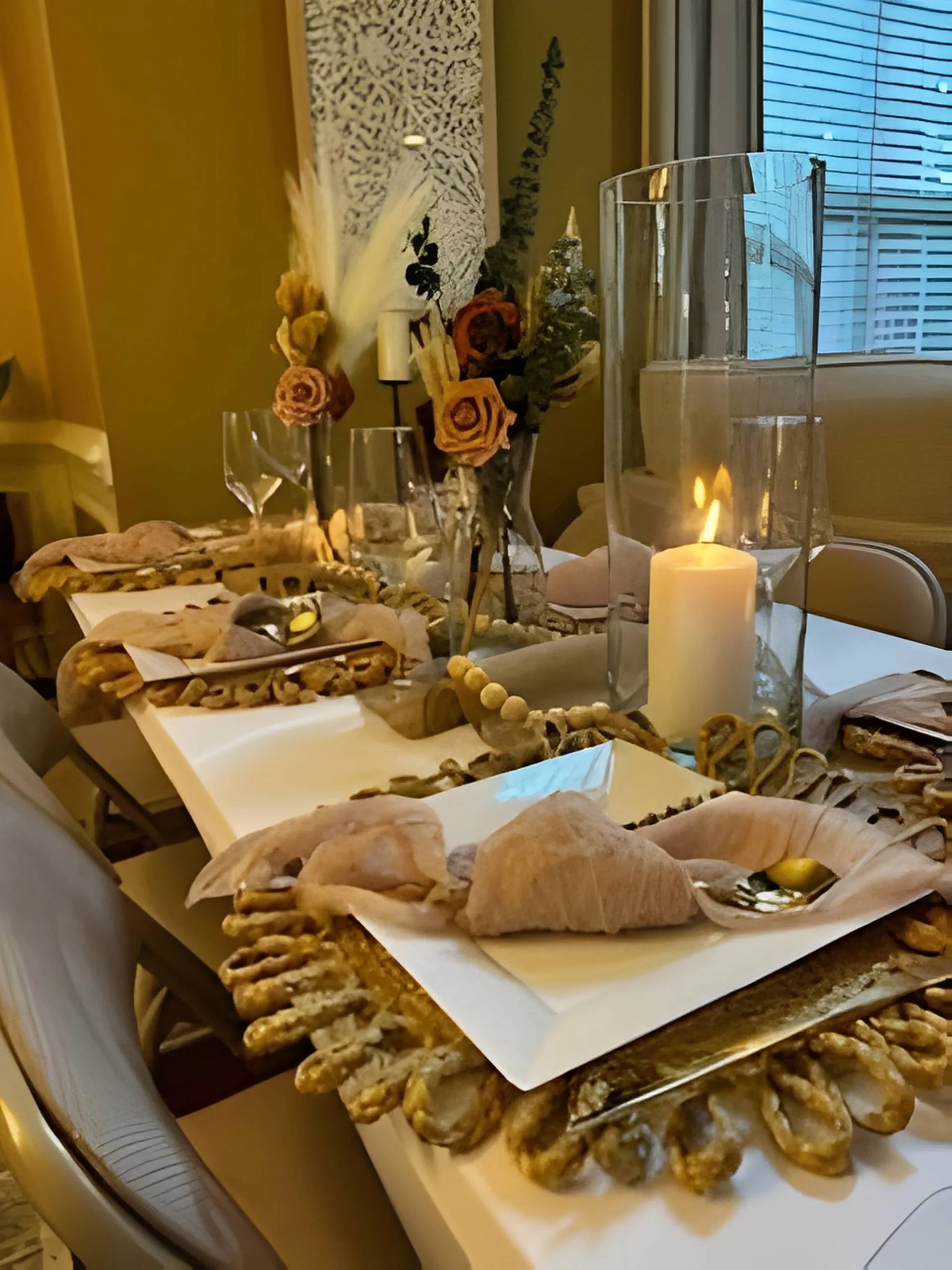 Intimate dining table styled with candles, dried florals, neutral linens, and layered textures