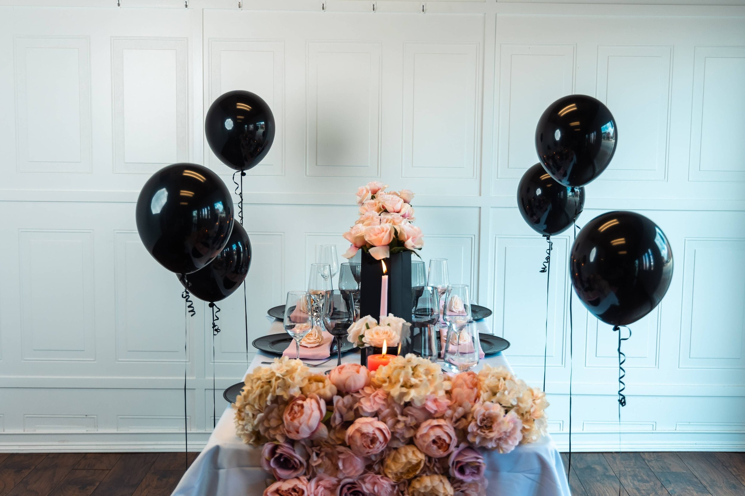 Elegant event table styled with blush florals, black accents, and candlelight