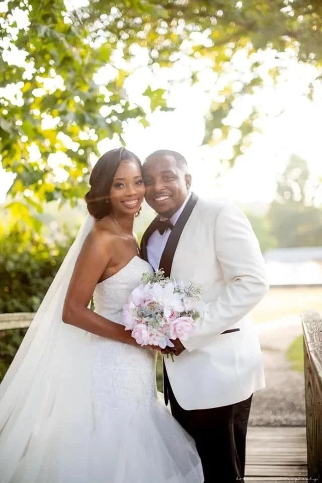 

Bride in a strapless wedding gown holding a bouquet with a flowing veil outdoors