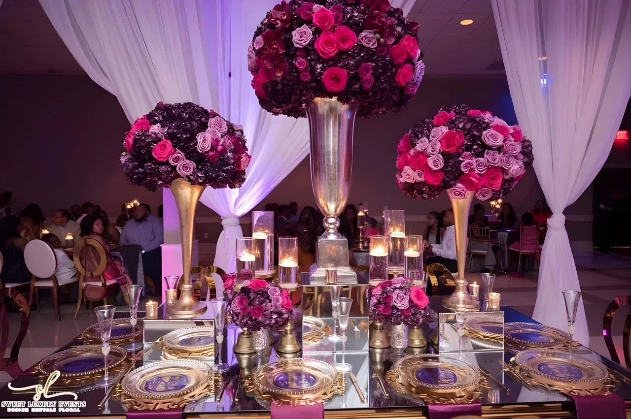 Formal wedding reception setup featuring long tables, gold accents, floral arrangements, and candlelight décor.