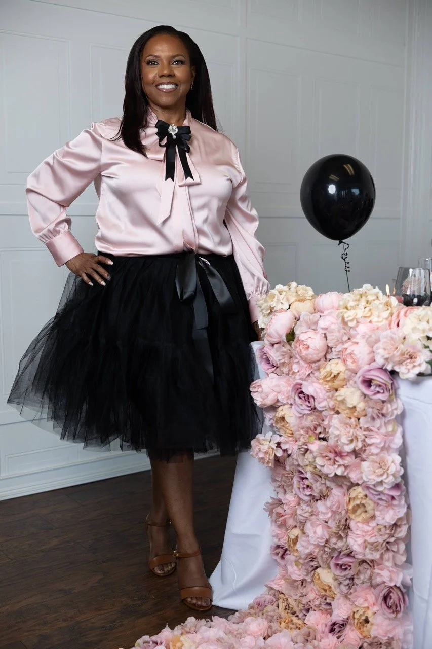 Founder of Booked standing beside an elegant floral tablescape styled in soft blush and black tones
