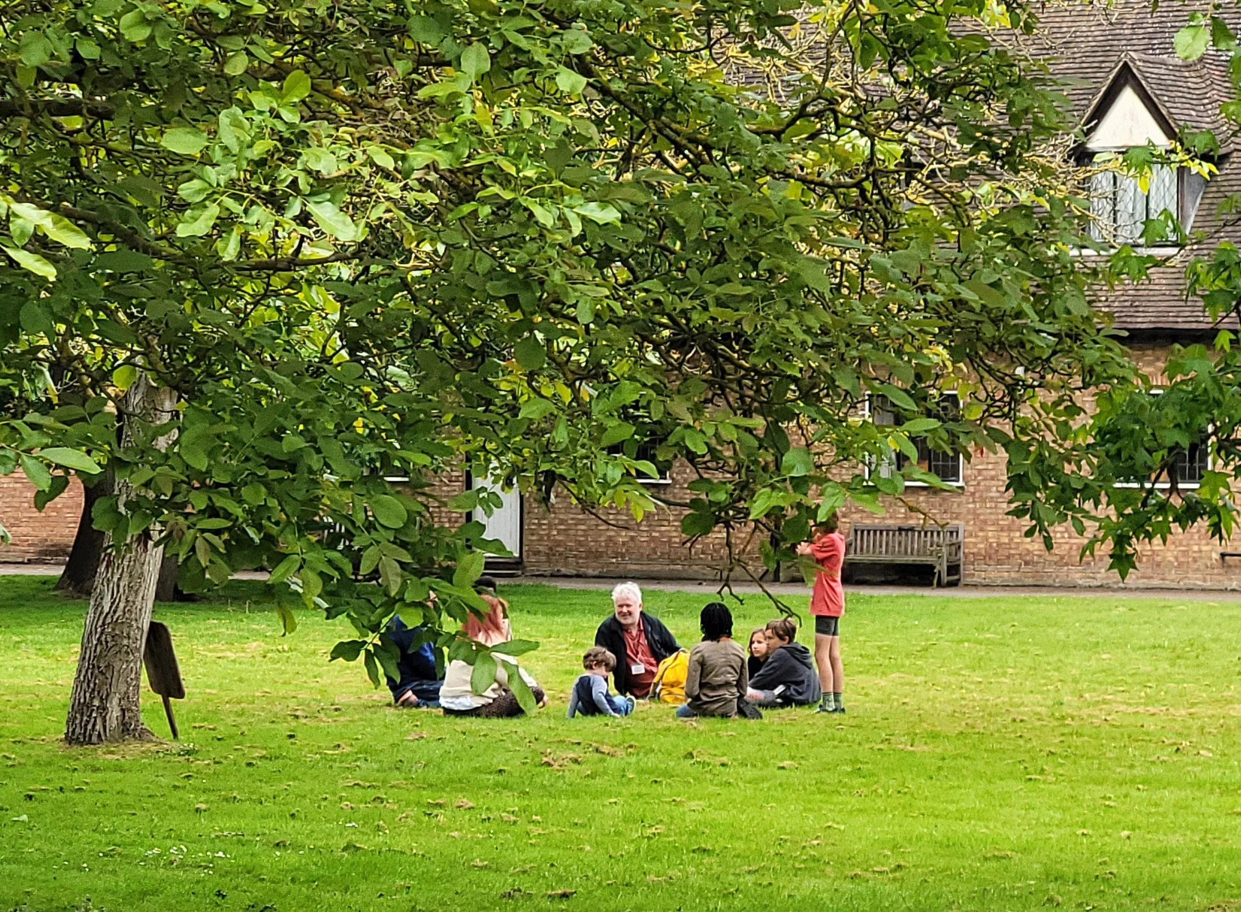 Two adults and several children sit under a tree at a previous FUSE Festival
