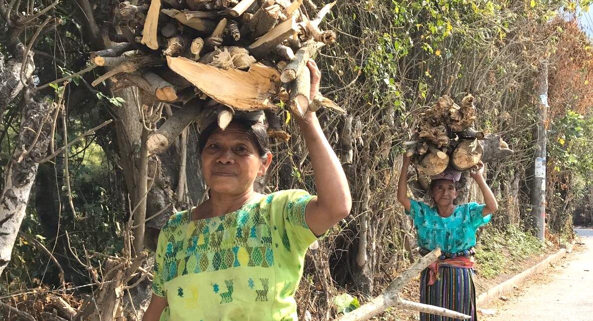 Flavia (right), carrying wood for her open cooking fire