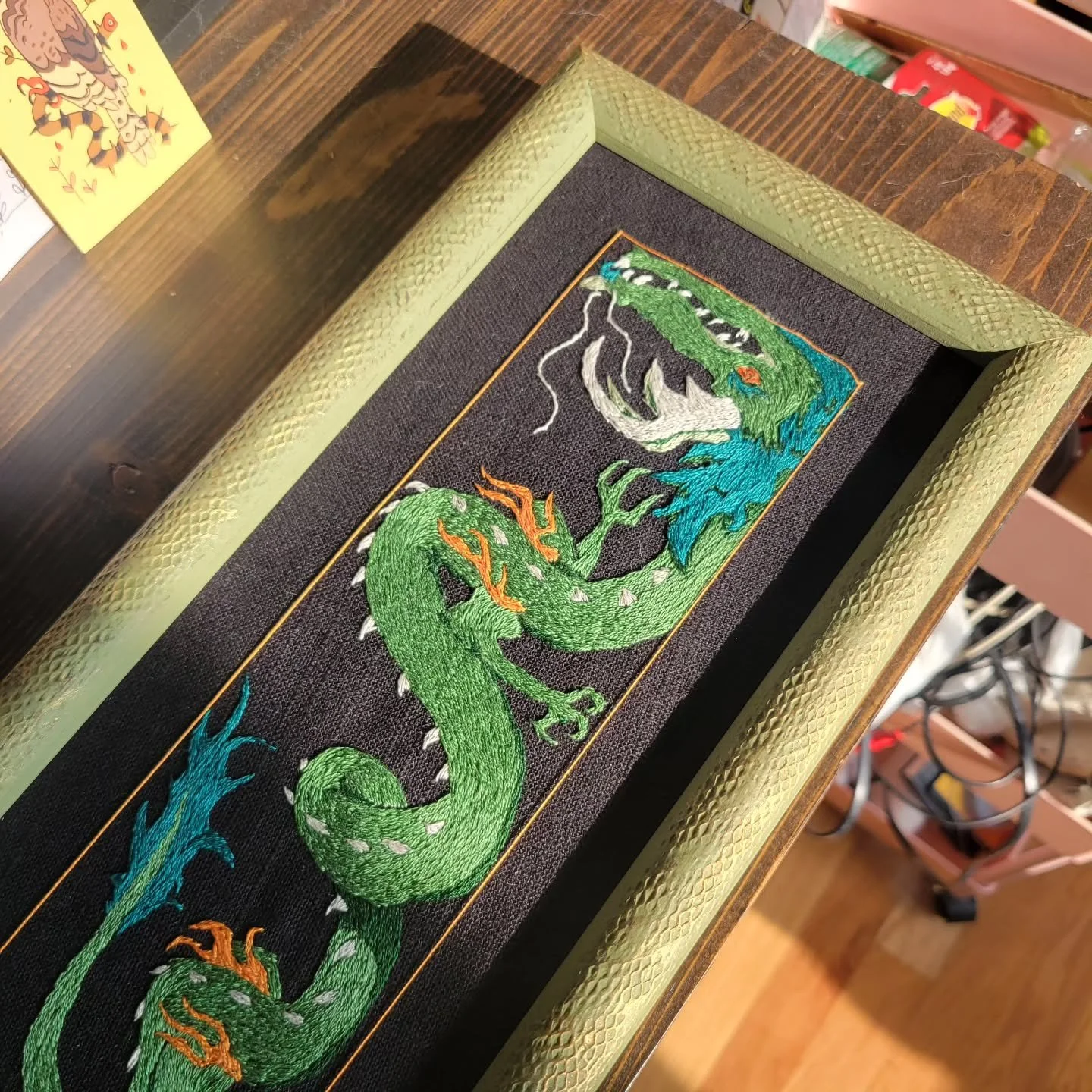 Been trying to capture the sheen on this dude but trust me it looks even better in person 😎 the frame's gold highlights also capture the light in a more subtle way but unfortunately my camera is weak and pathetic 😅

#embroidery #dragonart #fantasya