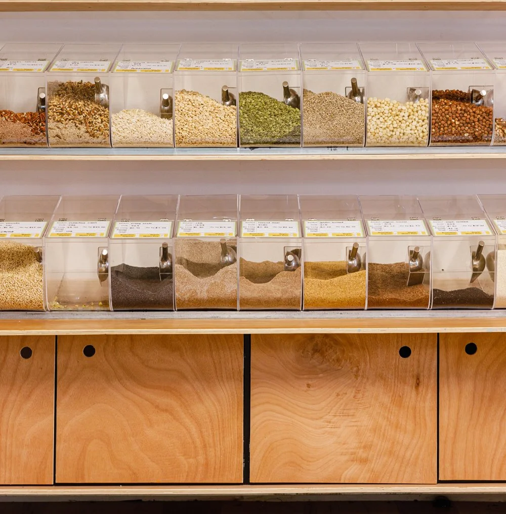 Bulk bins filled with various nuts, seeds, and seasonings at a grocery store.