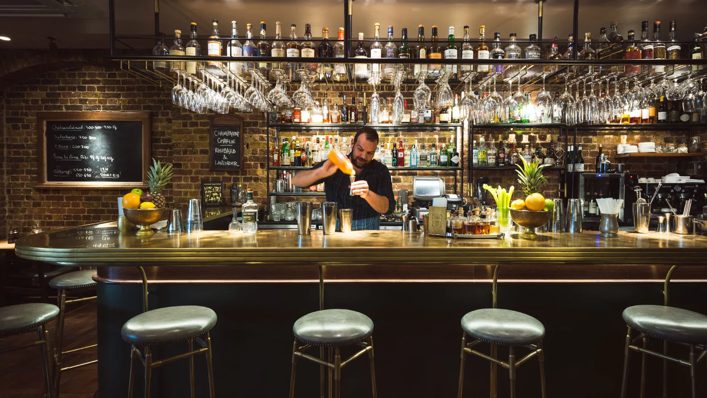 Hawksmoor bar with glass racking over and bar stools.