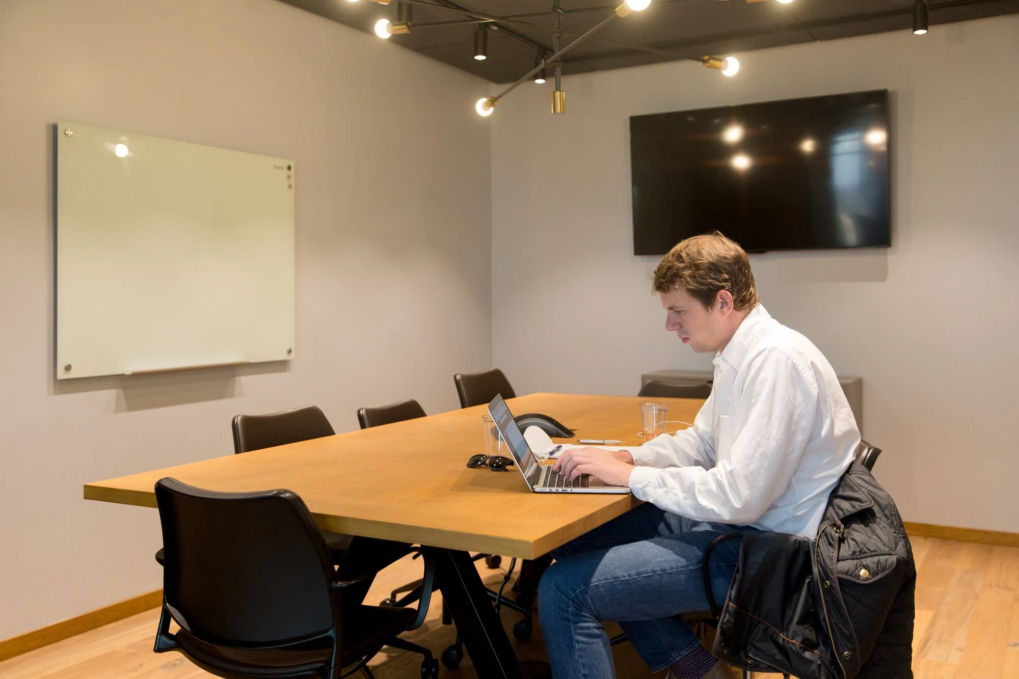 A man working on a MacBook at a conference table