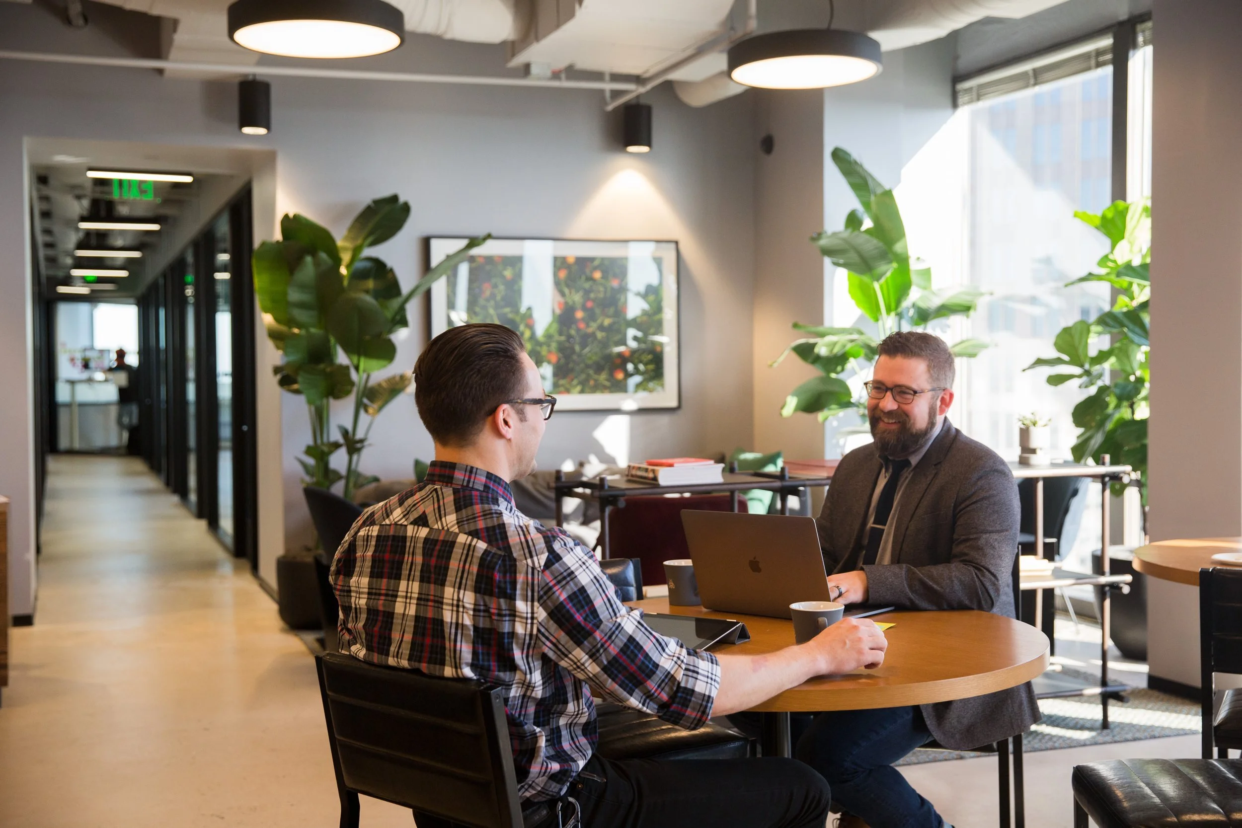 Two colleagues meeting over a MacBook in a Charlotte office
