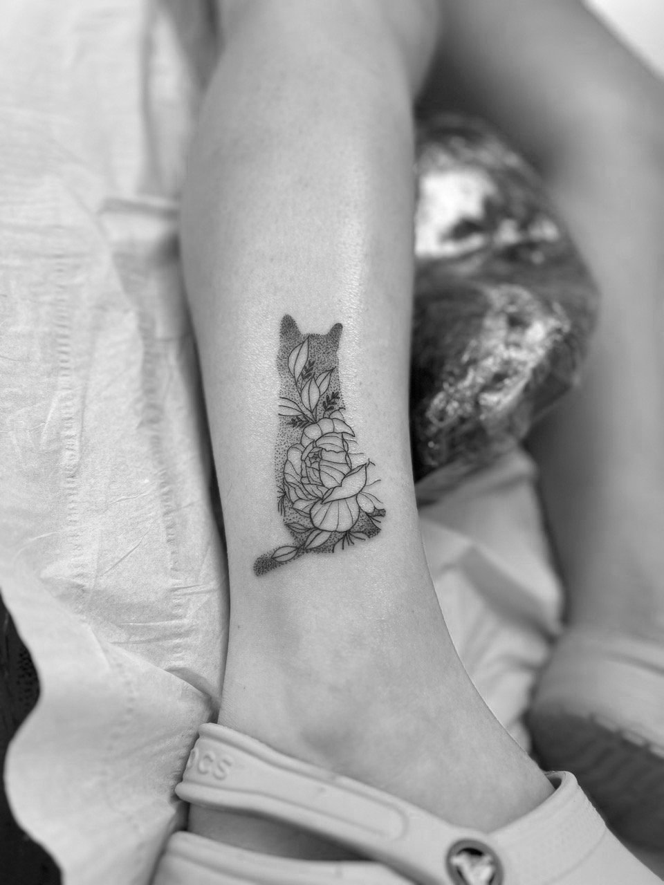 Fine line tattoo of cat silhouette and flowers by Math