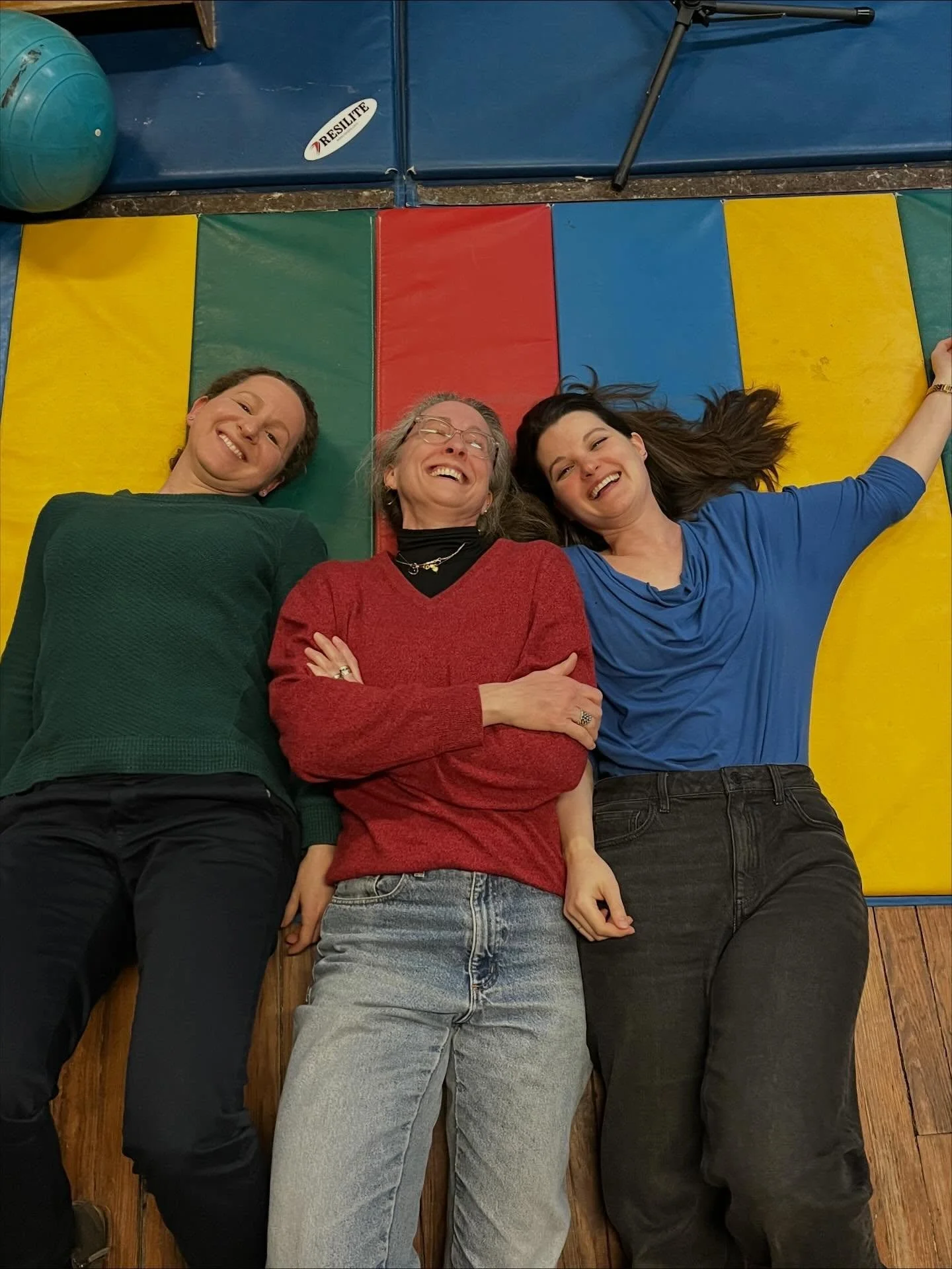 When you&rsquo;re soooooo in sync with your choir friends that you dress like your rehearsal venue. 

💚❤️💙

[ID: A photo of three singers, each wearing a different-colored sweater: green, red, and blue. They are smiling and lying on a striped mat, 