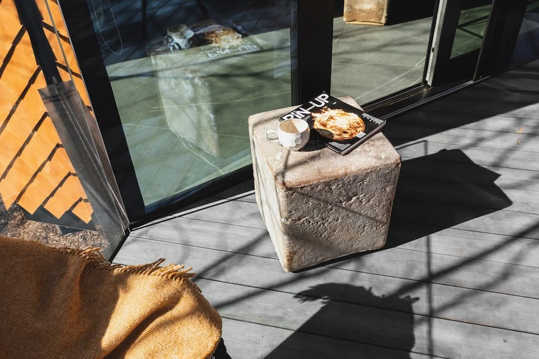 A mushroom cement coffee table with a magazine and coffee cup on top