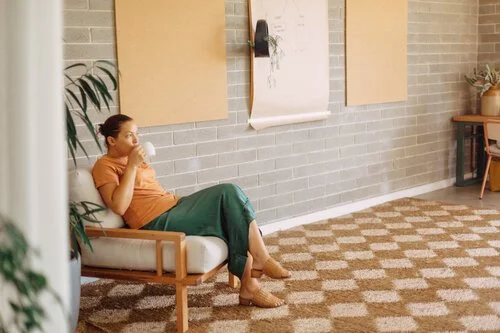 Woman sitting on a armchair sipping a drink from a mug
