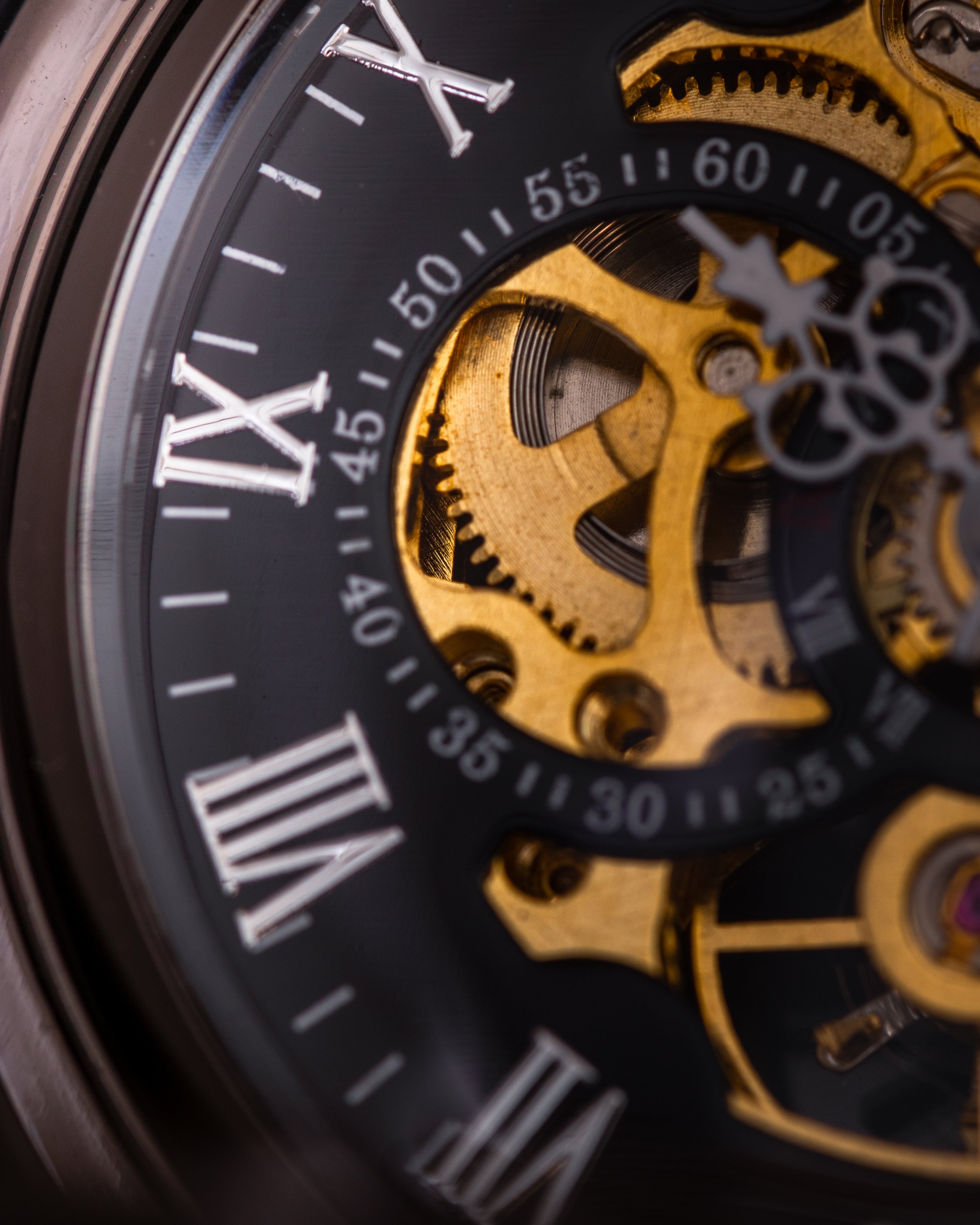 Close-up of a mechanical watch movement showing gears and a black dial with white Roman numerals