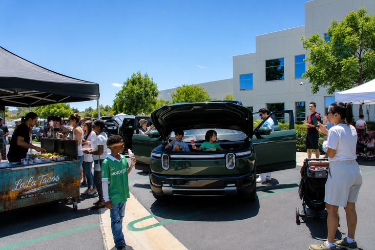 Families enjoying a Rivian Family Day event with LaLa Tacos & Churros catering next to a Rivian vehicle.
