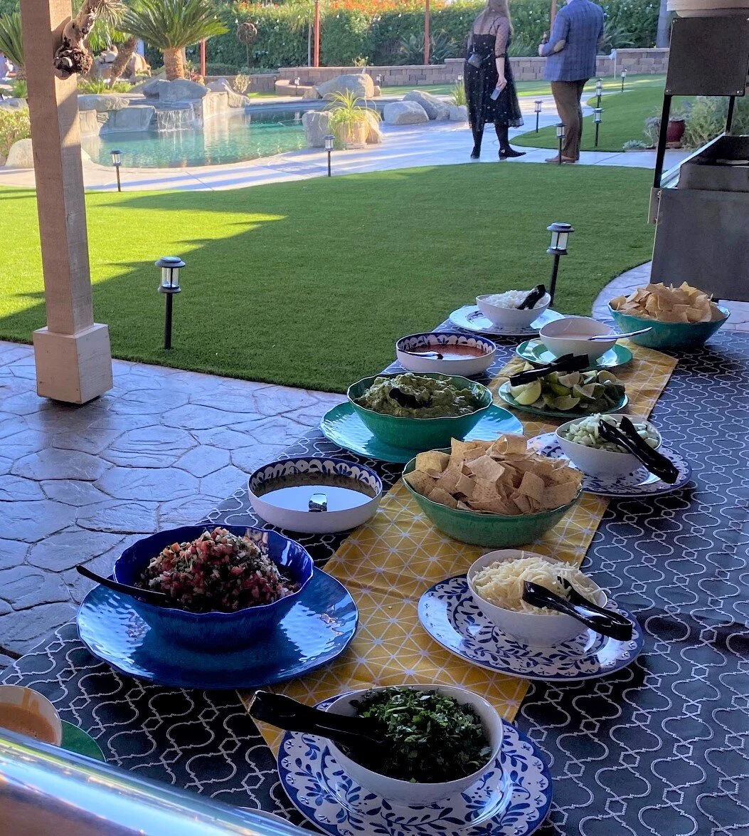 Elegant poolside taco bar catering setup at a Southern California private estate, featuring fresh guacamole, artisan salsas, and premium toppings displayed in decorative ceramic bowls by LaLa Tacos.