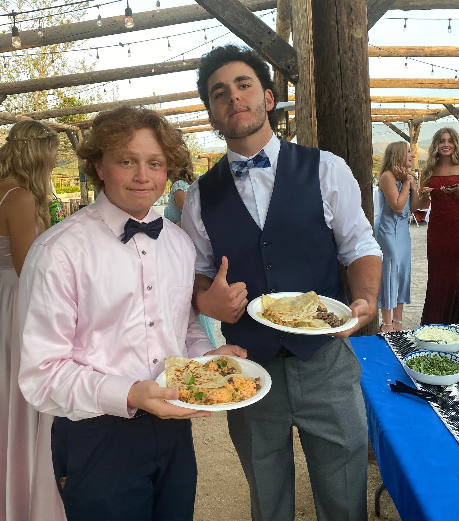 Dressed-up guests holding loaded plates of fresh tacos and handmade quesadillas at a high-end graduation taco party catered by LaLa Tacos in Southern California.