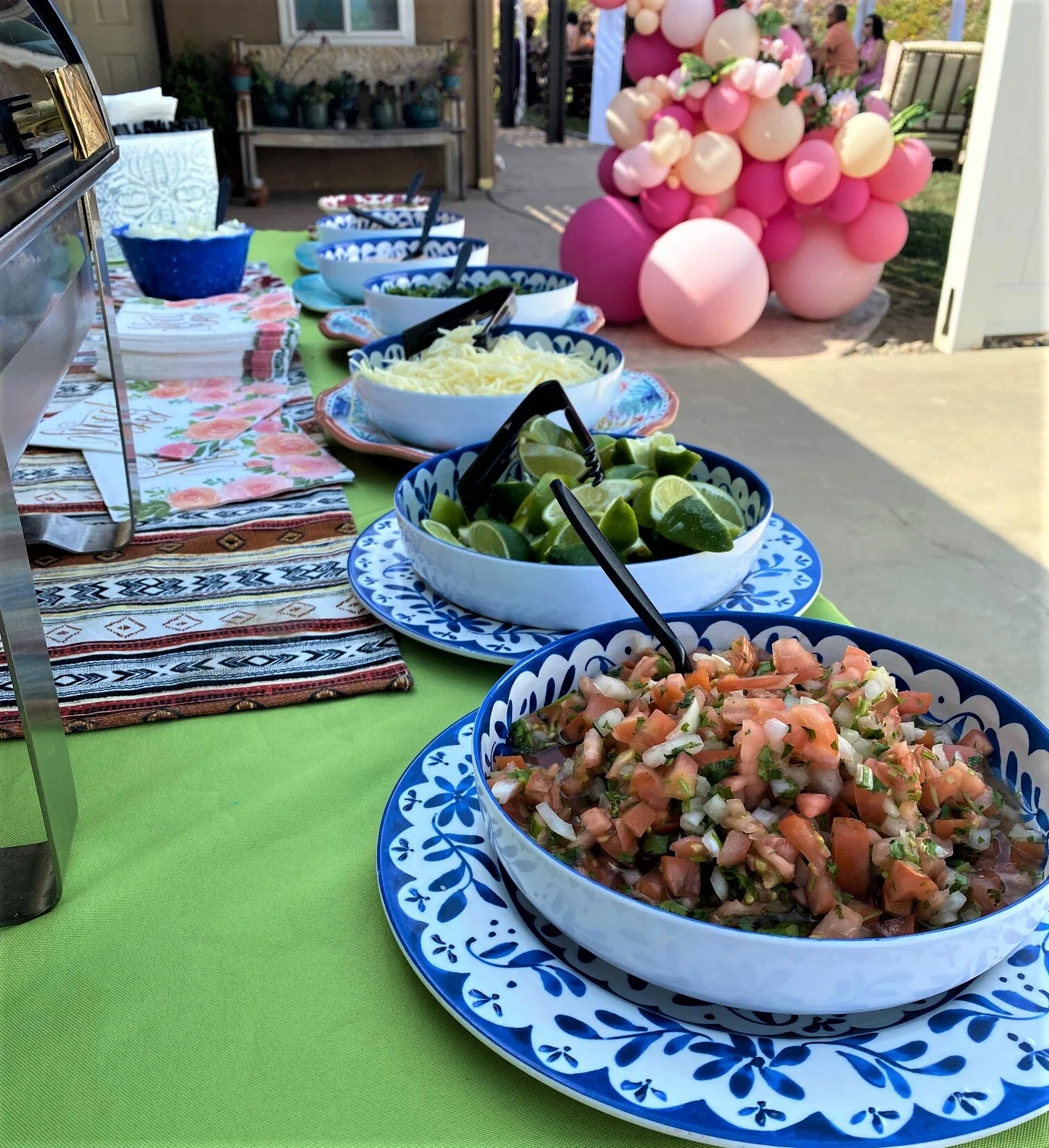 Close up of an elegant outdoor taco bar in Temecula, displaying fresh pico de gallo, lime wedges, and premium toppings in beautiful blue and white ceramic bowls by LaLa Tacos.