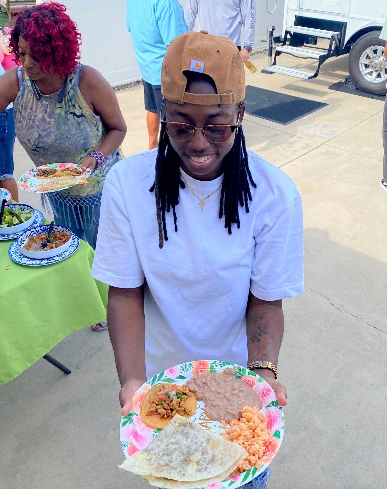 A guest holding a full plate of tacos, quesadillas, rice, and beans at a Murrieta backyard party.
