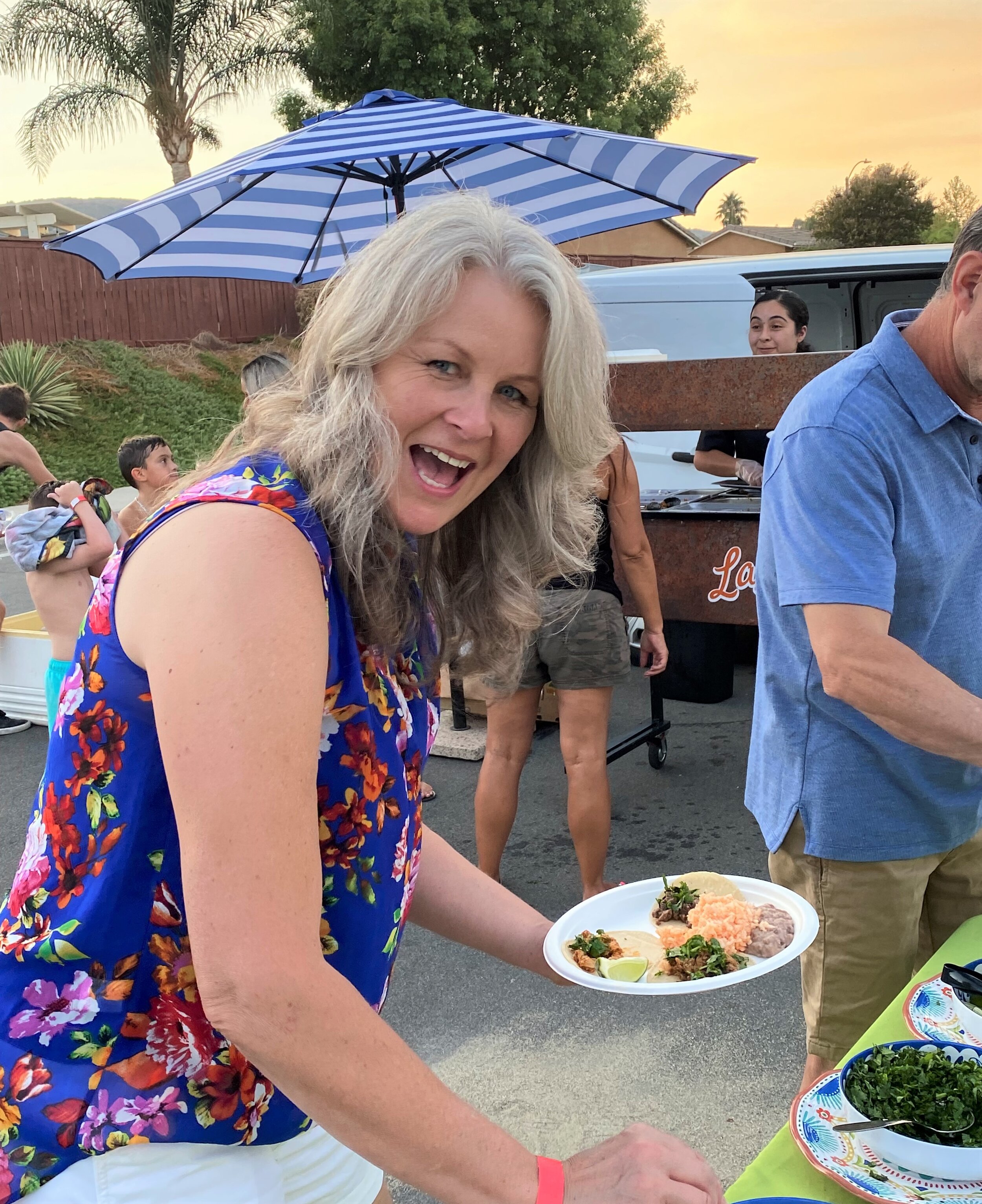 A guest holding a plate of tacos at a neighborhood block party in Lake Elsinore featuring mobile taco catering.