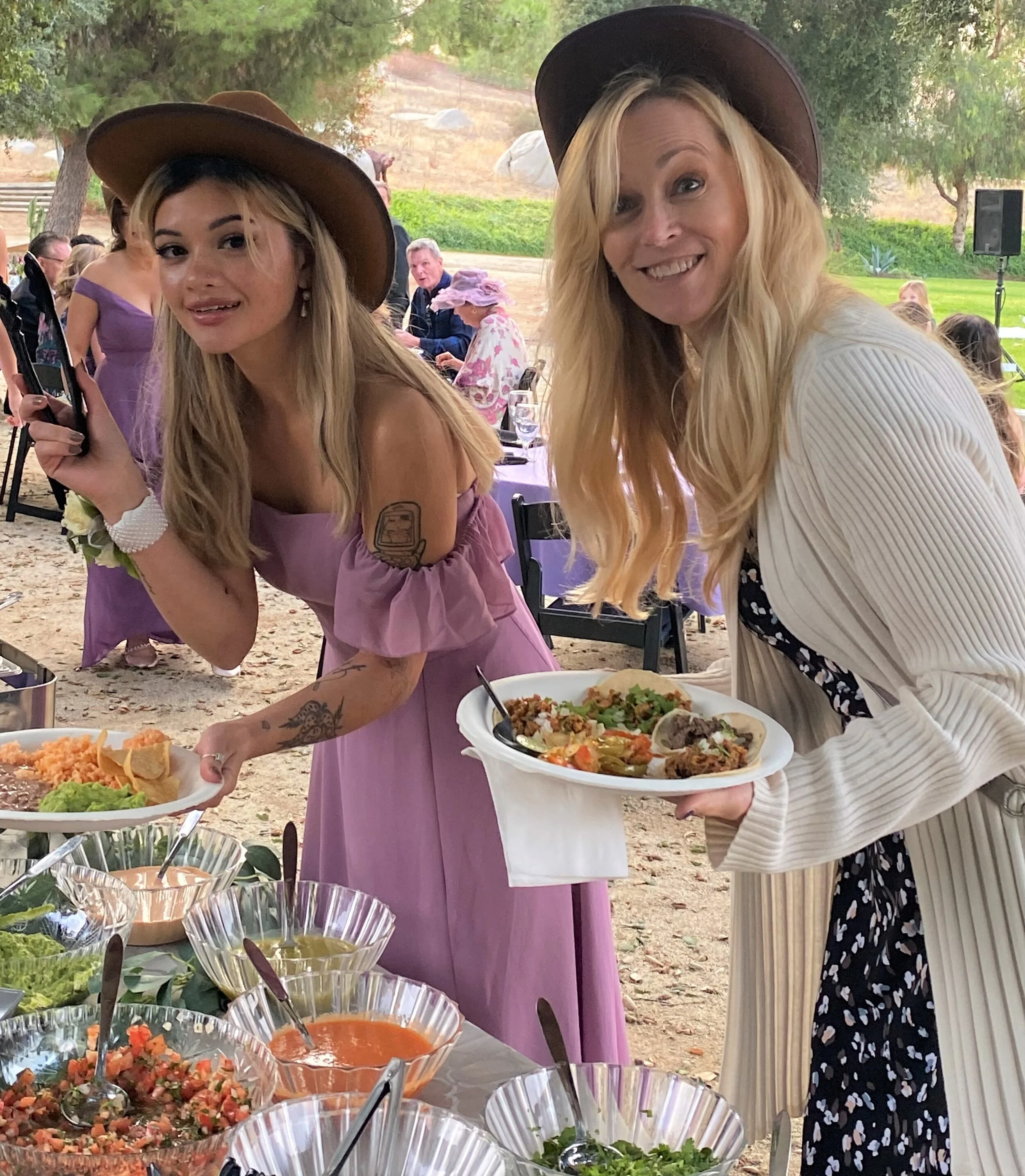 Guests enjoying a taco bar at an outdoor wedding featuring fresh tacos, salsa bar toppings, and on-site taco catering.