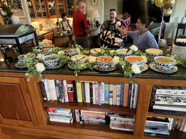 Expansive indoor luxury taco bar setup on a granite kitchen island featuring artisan salsas, fresh floral greenery, and premium serving ware for a private residential catering event.