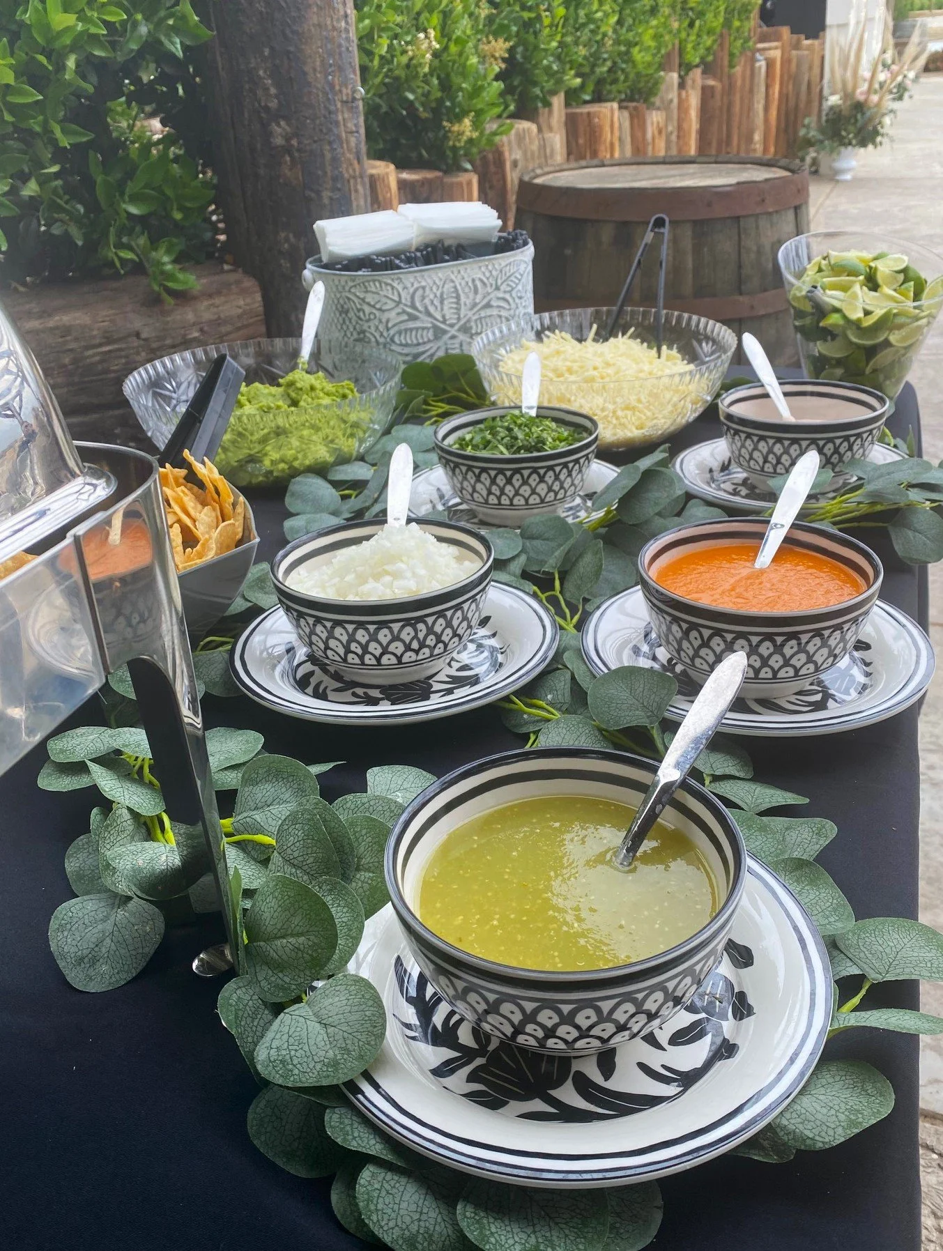Taco Bar CaterinA boutique taco catering salsa station featuring fresh green and red salsas, guacamole, and toppings served in decorative patterned bowls with eucalyptus leaf accents.g