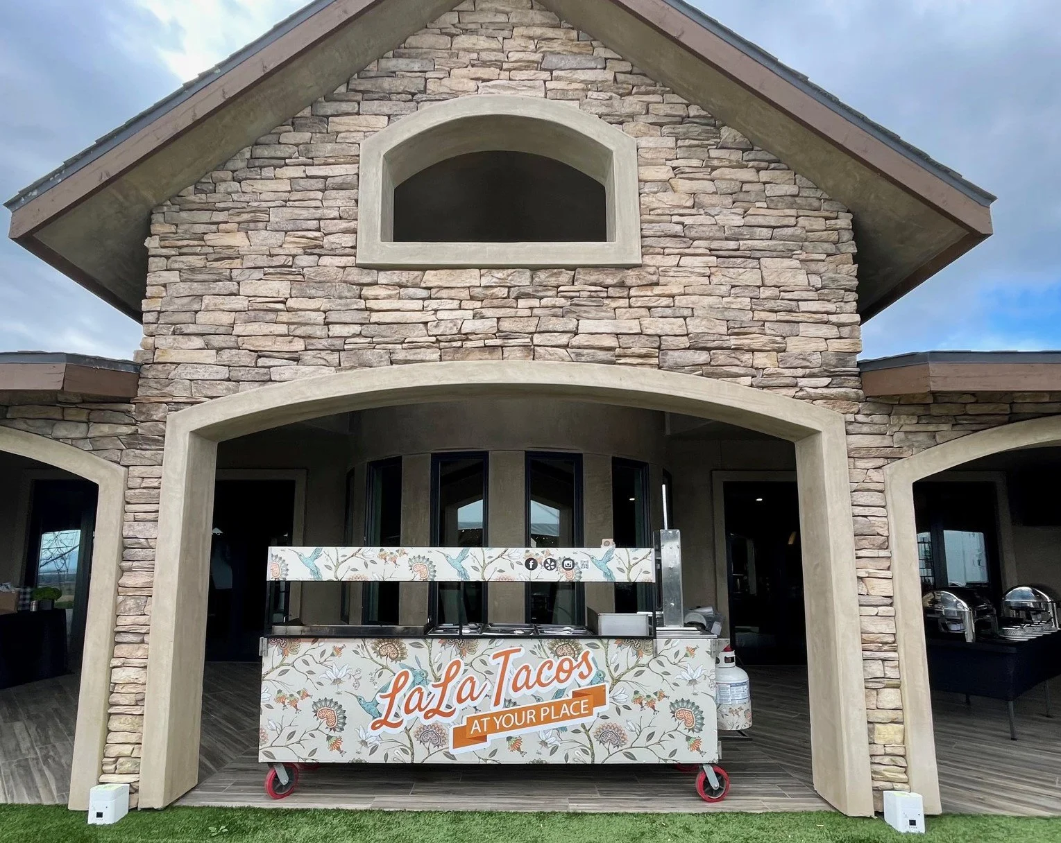 Artisan taco catering cart positioned in a beautiful stone archway for a luxury estate wedding