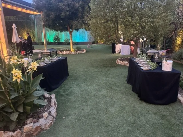Dual premium taco bar setups with black linens and decorative ceramic bowls staged on a manicured lawn for a high-capacity luxury wedding in Los Angeles.