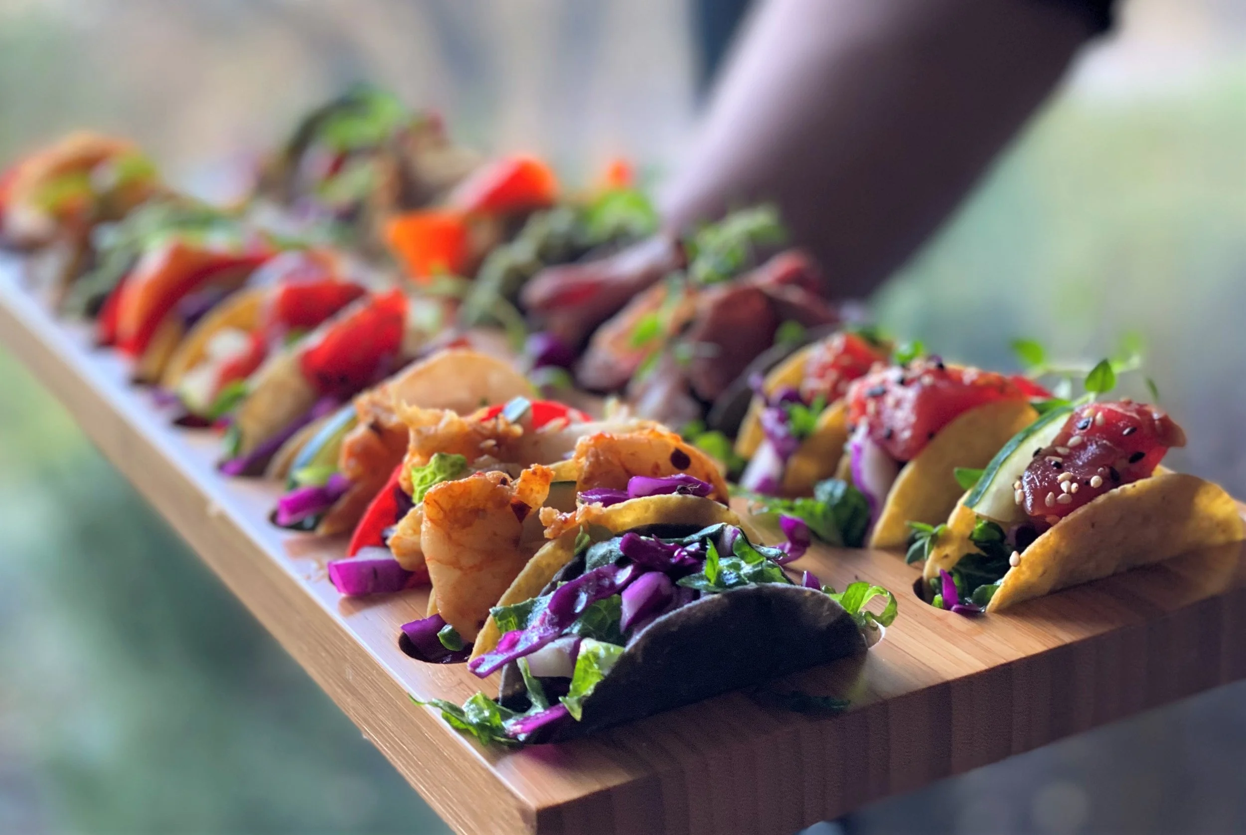 A luxury wooden tray of artisan mini taco appetizers including ahi tuna and shrimp being served at an upscale wedding cocktail hour