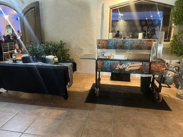 Custom patina wrapped live action churro dessert cart set up indoors at a luxury wedding and corporate event venue.