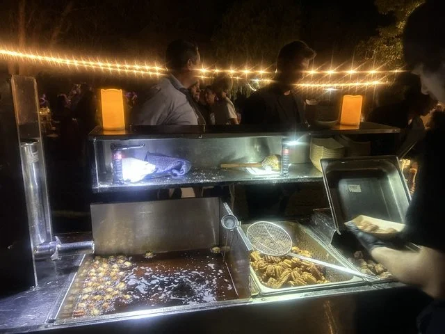 Live action dessert catering cart frying fresh churros under string lights at an Orange County wedding.