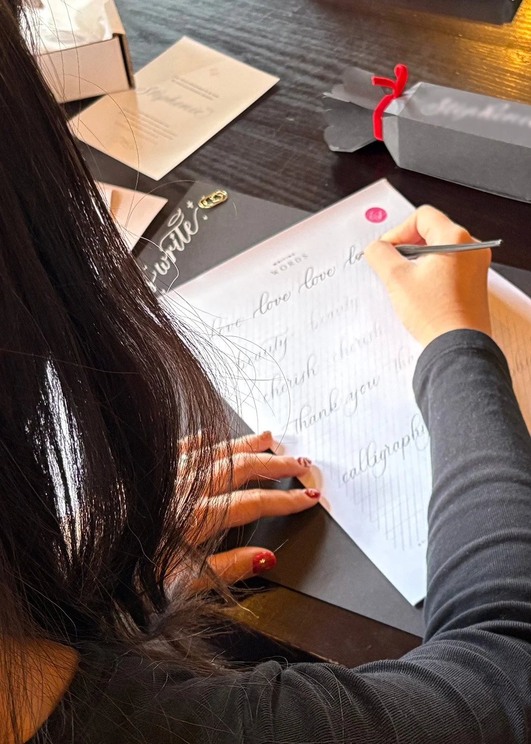 A woman writing with a calligraphy pointed pen on a pract