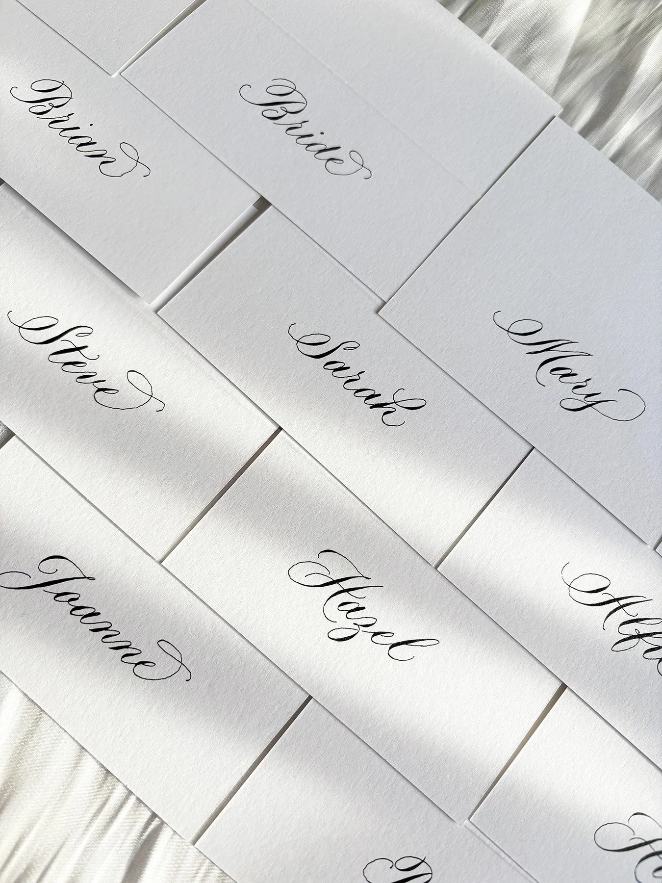 Handwritten place cards with calligraphy laid flat on a table.