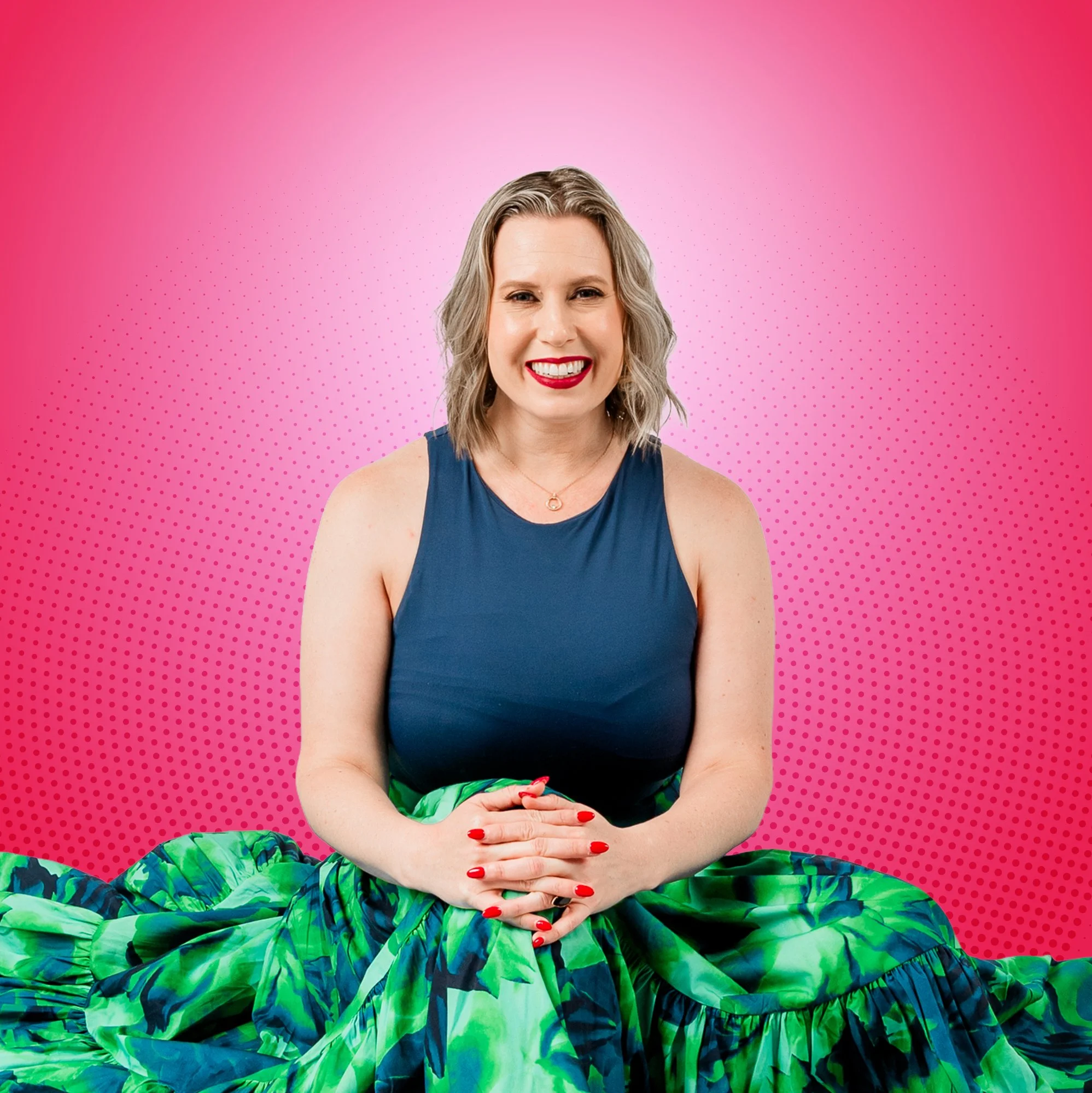 Sally Prosser, in a blue sleeveless top and a green patterned skirt, sitting with her hands clasped, against a pink background with a dotted pattern.
