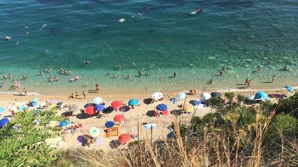 The coastline of Spiaggia Guidaloca with sunbathers and and beach umbrellas