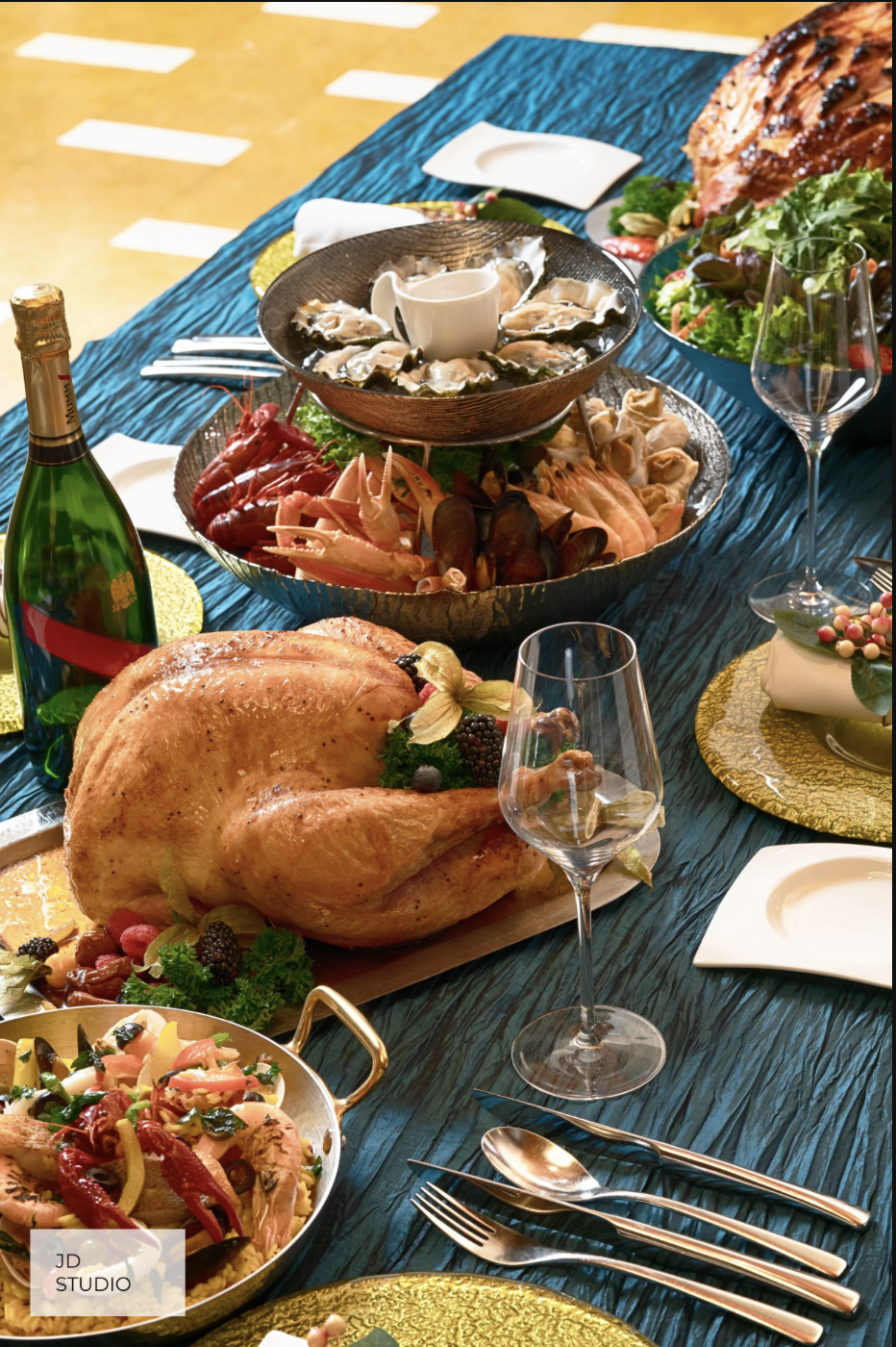 A festive table with a roasted turkey, seafood platter, salads, wine, and decorative tableware.
