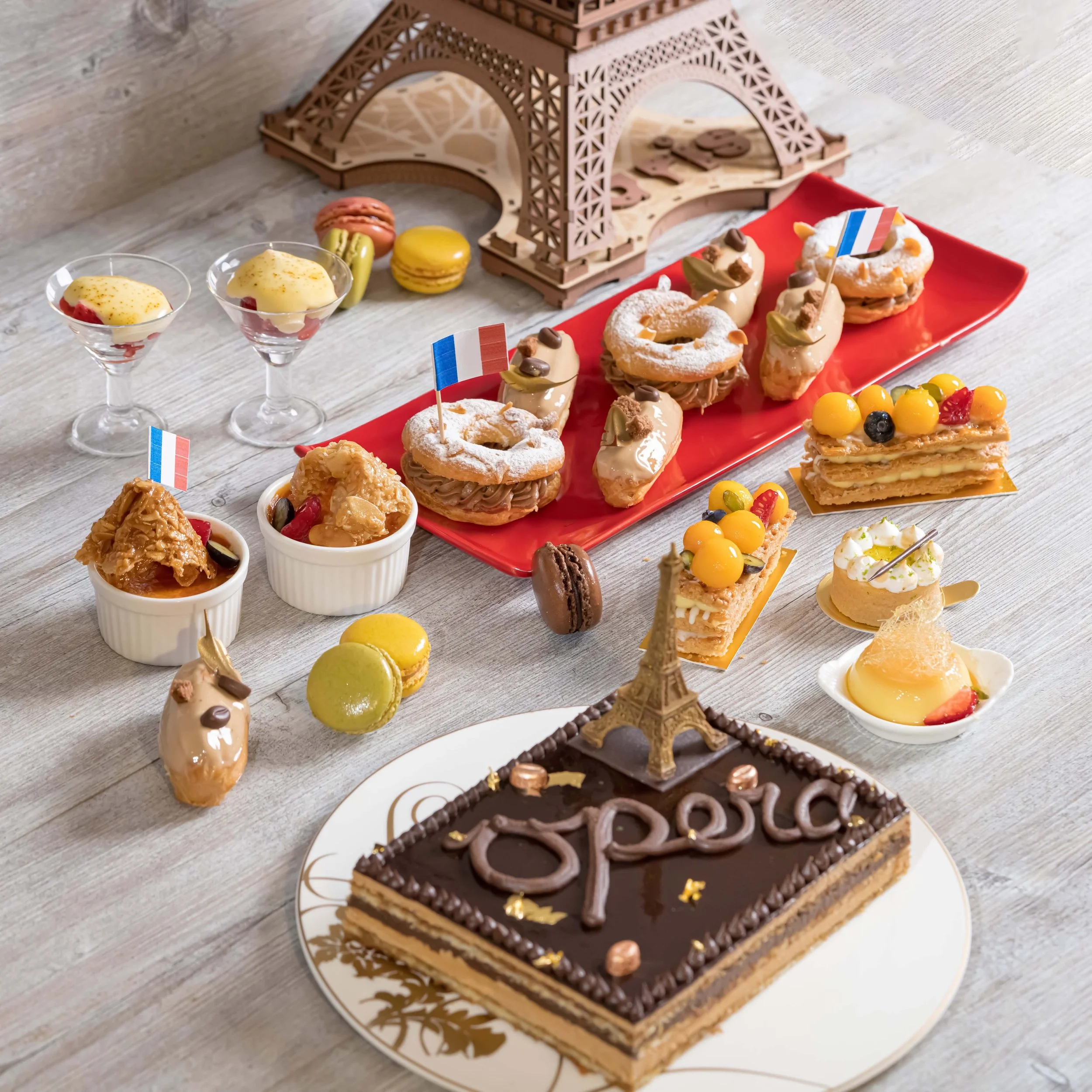 Assorted French pastries and desserts on a table with a miniature Eiffel Tower chocolate decoration.